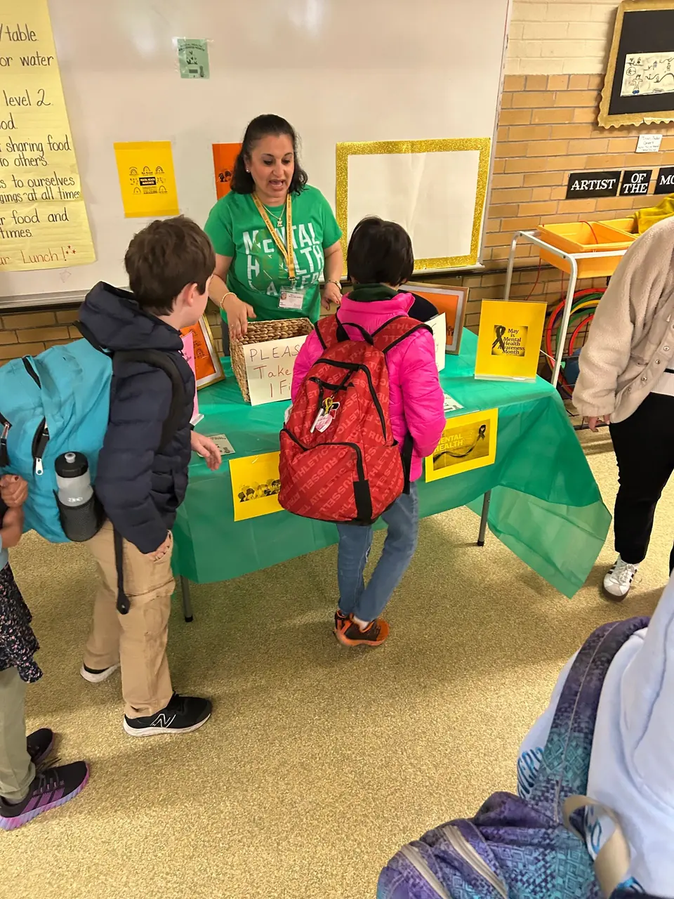 Two school psychologists at a Mental Health Awareness table talking with students