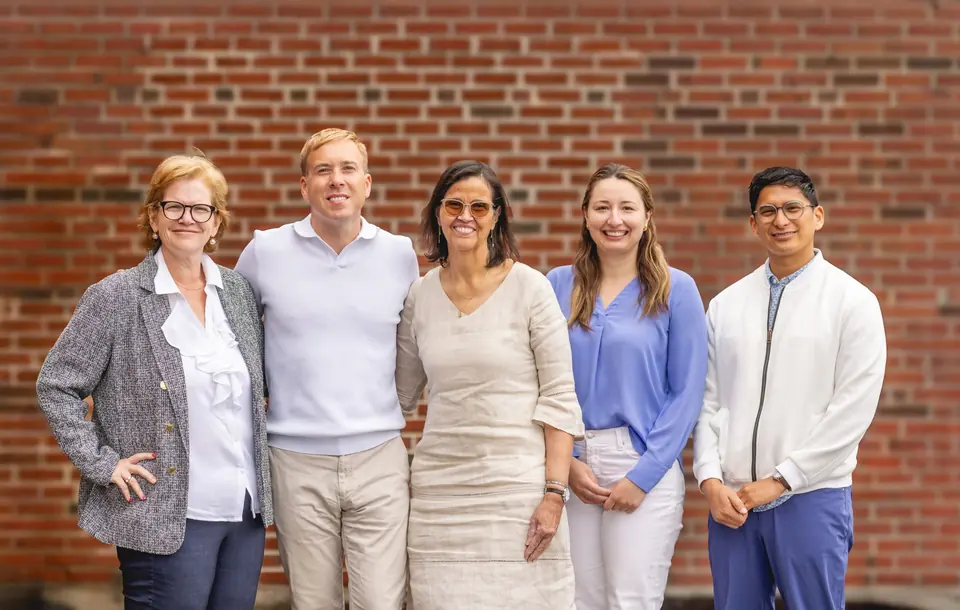 Members of the Behavioral Health Services leadership team standing together in front of a brick school building