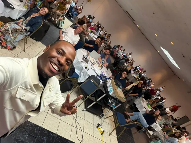 Dr. Byron McClure taking a selfie with a room full of Boston school psychologists at round tables behind him